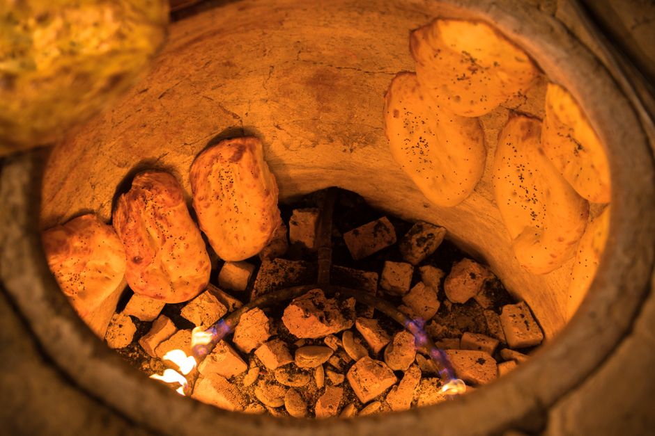 Fresh naan baking inside a tandoor oven