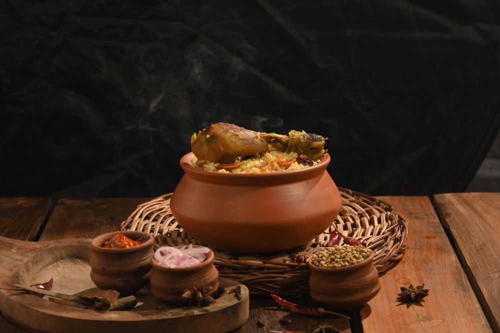 Chicken dum biryani steaming in a clay pot with spices